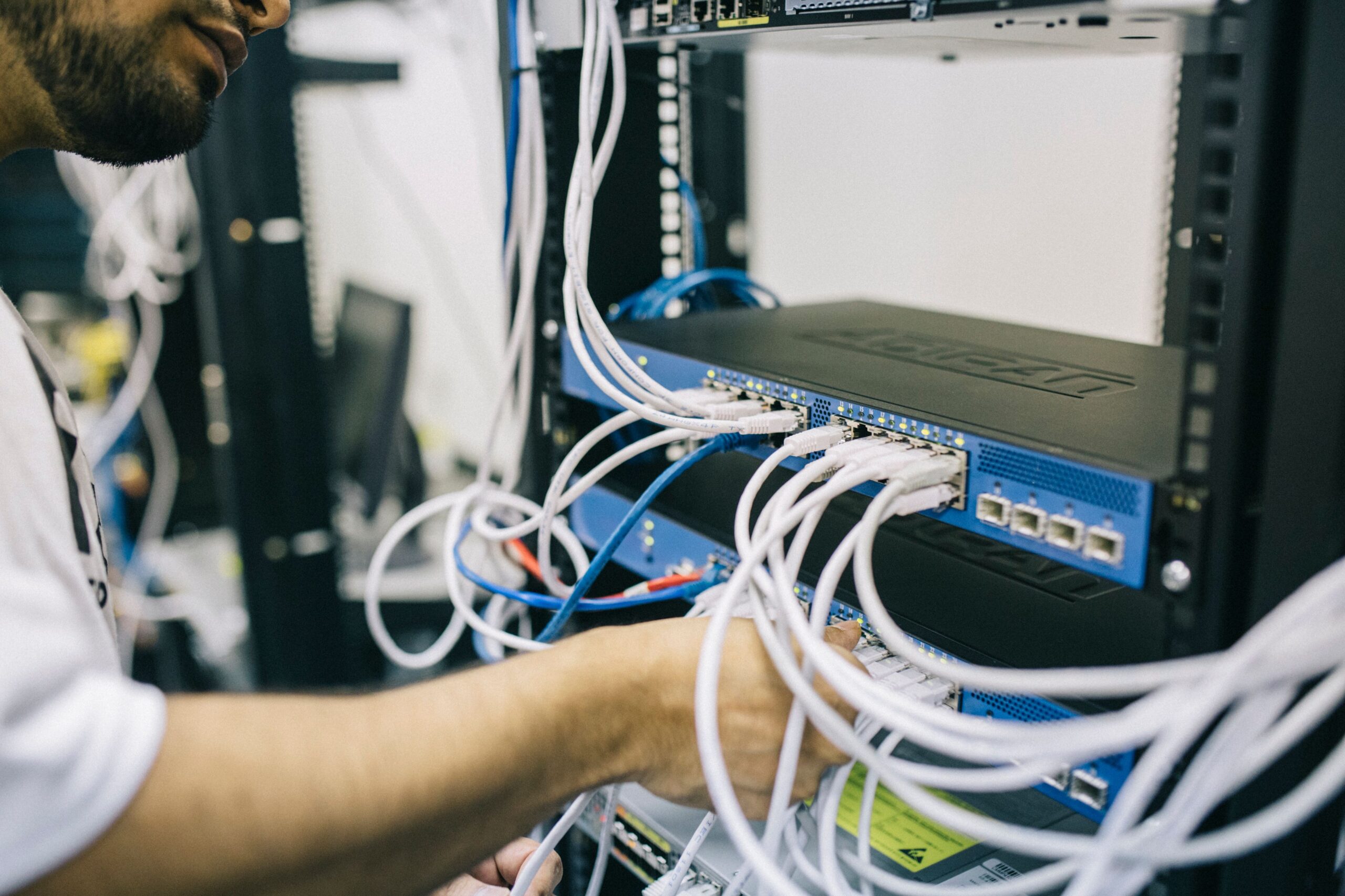 Engineer checking network cabling and equipment inside a communications cabinet.